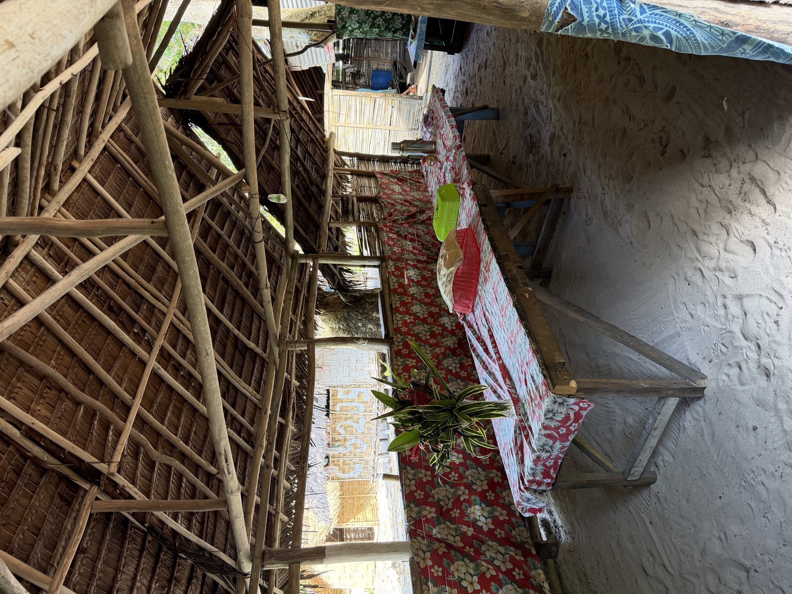 Dining area with a long table set for meals under a traditional thatched roof