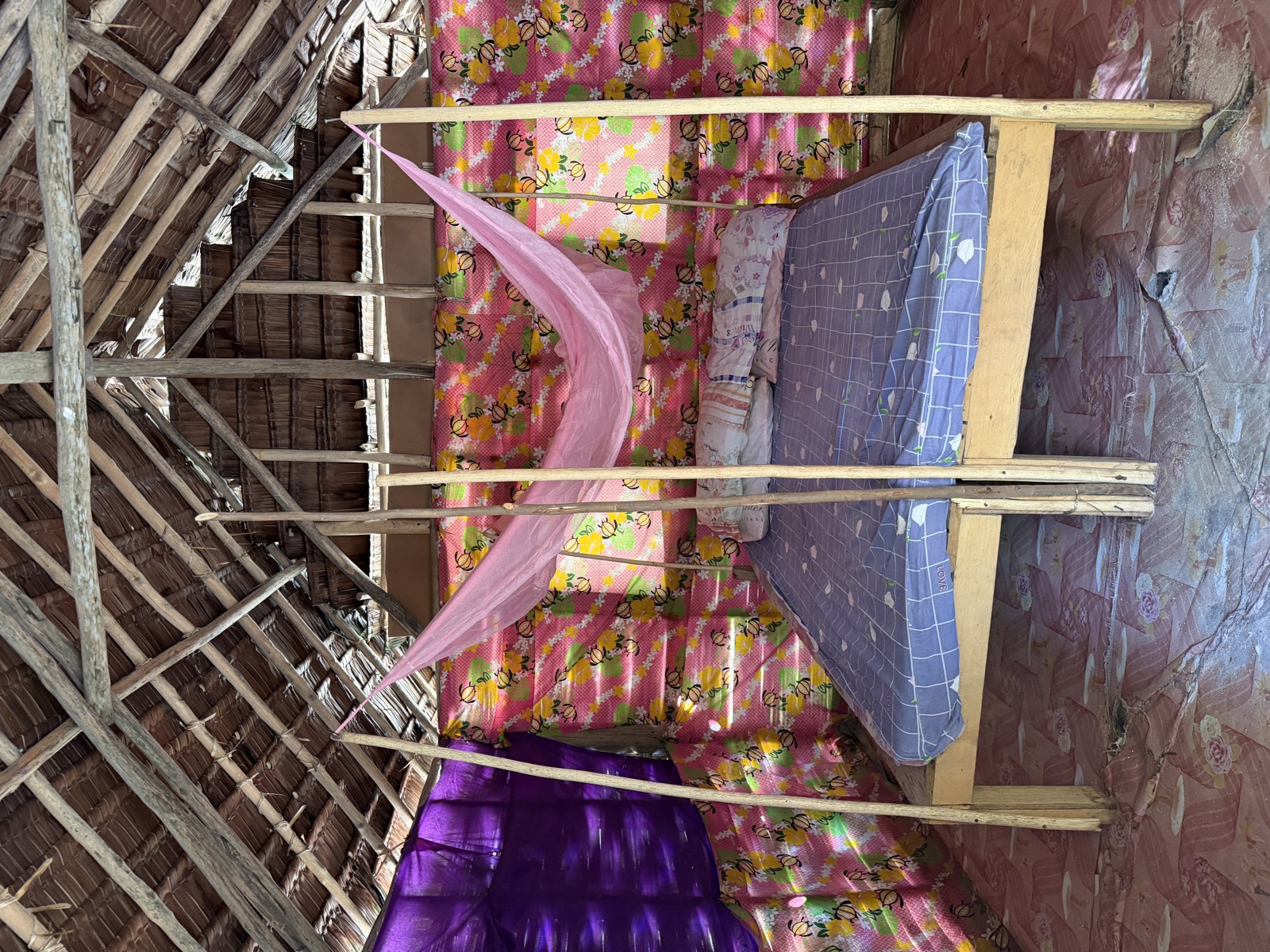 Bed with mosquito net inside a thatched-roof bungalow